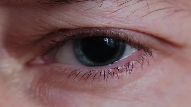 Macro shot of junkie man's eye with dilated pupil. Eye drops after a visit to an ophthalmologist. Drug influence concept.