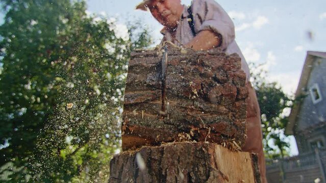 Man operating chainsaw to cut large tree trunk. Close-up photography for design and print. Lumberjack and woodworking concept.