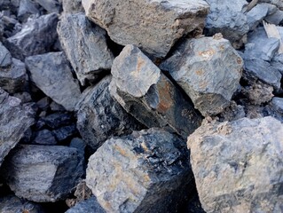 Texture of black coal in large stones. Large lumps of coal are dumped in a pile. The topic of natural resources and mining and backgrounds from them.