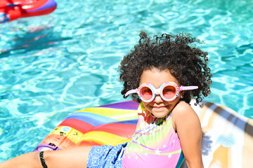 Smiling girl with goggles relaxing on a colorful float in the po