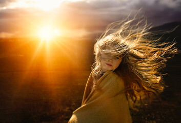 Beautiful young girl with hair blowing in bright sunny field