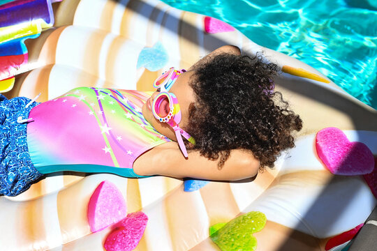 Girl relaxing on colorful float in the pool, sunbathing with gog