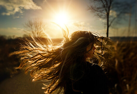 Young girl flipping long blonde hair in sunny field