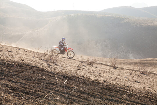 Skilled father and son riding on a dirt bike together in mountains.