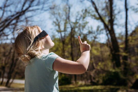 Child with solar filter glasses looking up at sun for solar ecli
