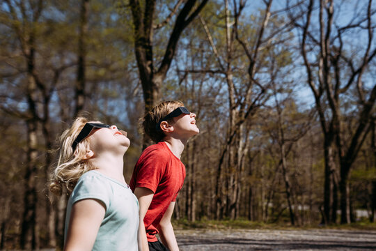 Children wearing solar eclipse glasses looking up at sun