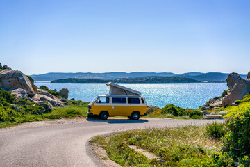 Old retro white and yellow camper van with rooftop on the coast