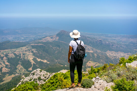 Back view of woman hiker looking at mountain landscape with sea
