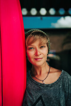 Portrait of young happy stylish woman with surfboard.