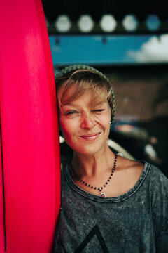 Portrait of young happy stylish woman with surfboard.
