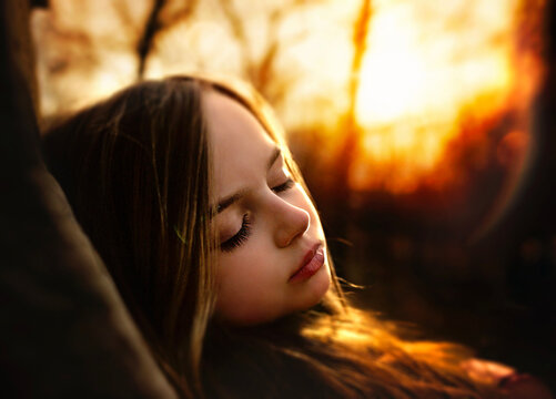 Beautiful young girl sleeping in warm sunny forest