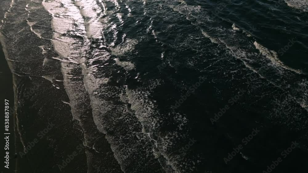 Poster aerial drone footage of the sea capturing abstract patterns of waves illuminated by backlight. the s