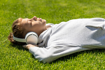 A boy relaxing on grass, listening to music