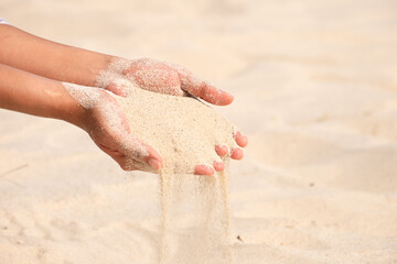 The woman's hand had a certain amount of sand, sand flowing from the woman's hand. desert background	