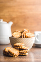 Chocolate Filled Cookies on a Wooden Table With a Cup and Pitcher in the Background
