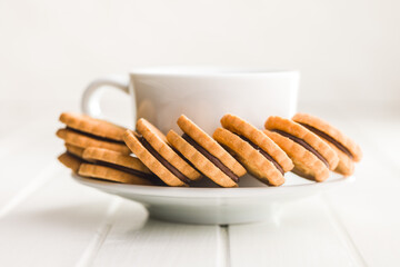 Chocolate Filled Cookies on a Saucer Beside a Cup