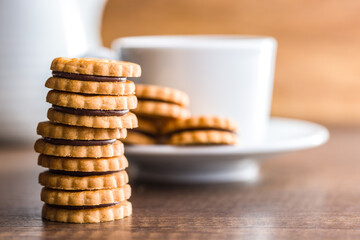 Chocolate Filled Cookies on a Wooden Table With a Cup and Pitcher in the Background