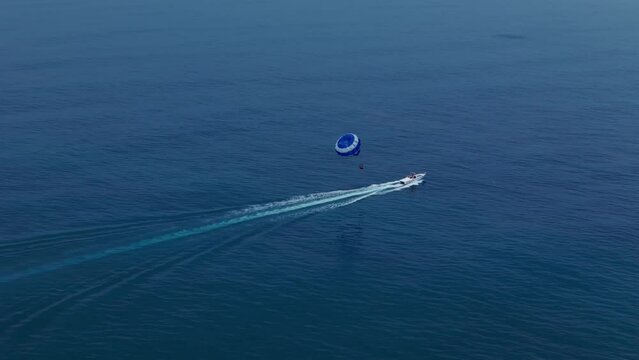 Flying with Parachute Behind a Boat Parasailing drone view