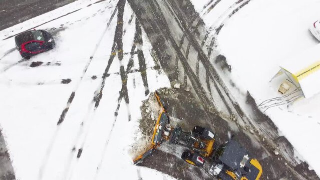 Aerial View of Snow-Covered Road with Snowplows at Work doring Snowstorm
