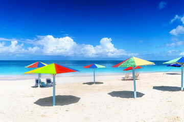 A beautiful, tropical beach with colorful umbrellas and turquoise ocean at the island of Antigua...