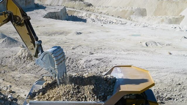 Yellow excavator loading soil into a dumper truck on construction site