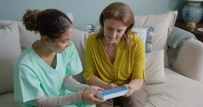 Caregiver Showing Senior Woman Medication in a weekly Pill box