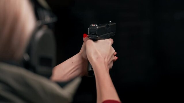 close up At a professional shooting range a military man controls the technique of shooting a pistol the first shot