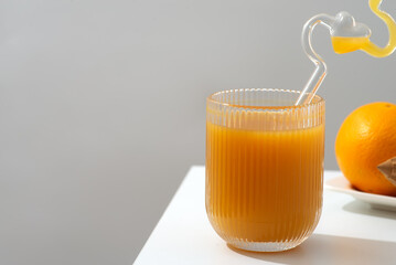 A glass of refreshing orange juice placed beside a plate of fresh oranges