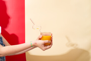 A woman is sitting at a table holding a glass of orange juice with a straw © YuliiaMazurkevych