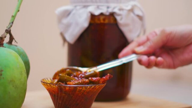 Close up shot of Mango Pickle in bowl with Raw mangoes in background in Gujarat, India. Gujarati pickle. Aam Ka Aachar. 