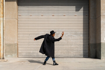Carefree young man enjoying day by dancing against shutter on sunny day