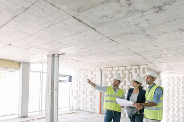 Male architects and female manager talking about architectural plan at construction site