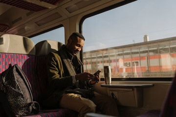 Stylish man using smartphone inside a train