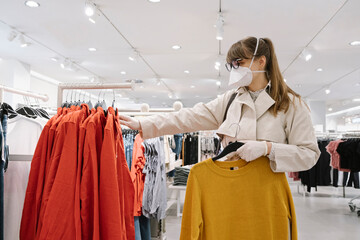 Woman with face mask and disposable gloves shopping in a fashion store