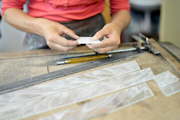 Close-up of woman working on piece of glass in glazier's workshop