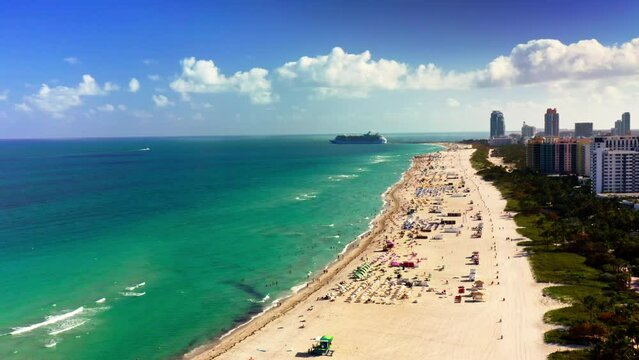 4k aerial footage. Views of Miami Beach boasting cruise liners, turquoise water, sandy shore of Atlantic ocean. Vibrant cityscape under clear blue skies perfect destination for urban beach vacationers