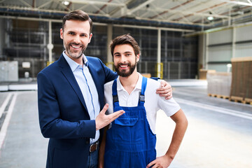 Portrait of happy businessman and worker in a factory