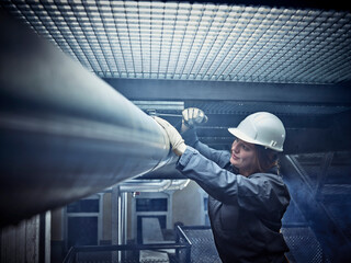 Craftswoman wearing hard hat working at pipe