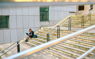 Businesswoman sitting on stairs, using laptop