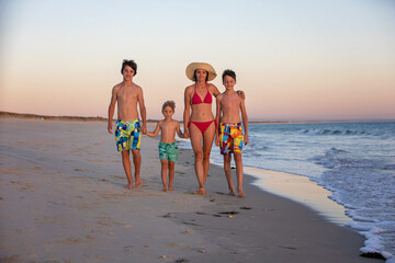 Happy children, boys, playing on the beach on sunset, kid cover in sand, smiling, laughing