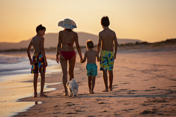 Happy children, boys, playing on the beach on sunset, kid cover in sand, smiling, laughing