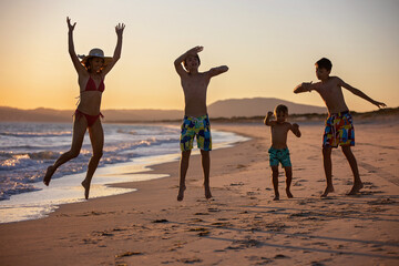 Happy children, boys, playing on the beach on sunset, kid cover in sand, smiling, laughing