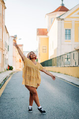 Woman with arms outstretched standing on road in city
