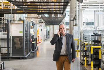 Businessman in factory shop floor talking on the phone
