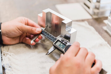 Detail of woman measuring metal workpiece