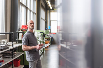 Man standing in modern factory holding product
