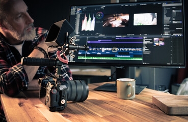 Photographe videaste devant un ordinateur en train de faire du montage et de la post-production...