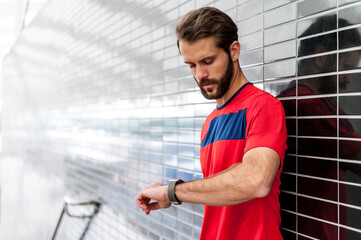 Man having a break from running checking the time on a smartwatch
