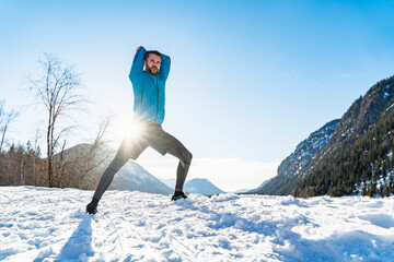 Germany, Bavaria, sportive man stretching in winter