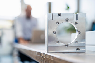 Metal workpiece in factory with businessman in background